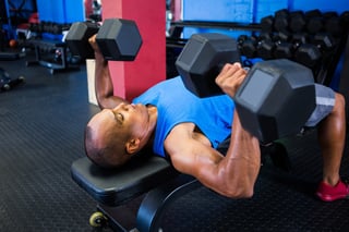 Male athlete exercising with dumbbells on weight bench in gym.jpeg